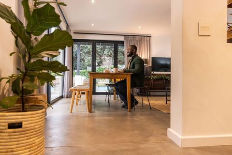 African american man working remotely at dining table in modern open-plan home office