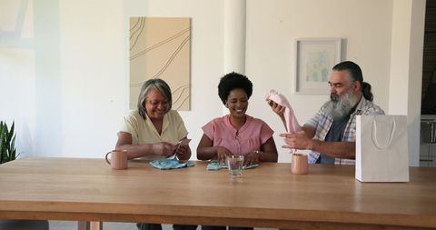Senior Couple and Young Woman Enjoying Gift Exchange at Home