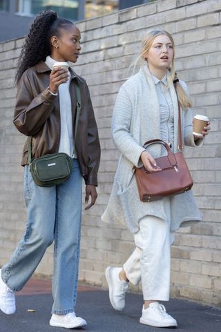 Friends walking and chatting while holding takeaway coffee, casual layered urban fashion
