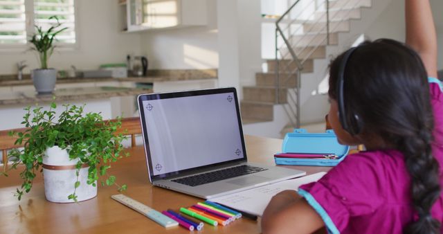 Hispanic girl sitting at table using laptop wearing headphones. at home in isolation during quarantine lockdown.