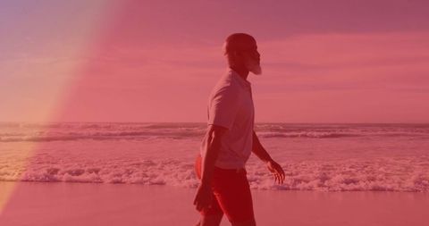 Man enjoying tranquil beach walk at sunset with ocean waves