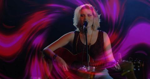 Energetic teenager singing and playing guitar on stage