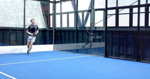 Male Athlete Swinging Racket on Blue Padel Court