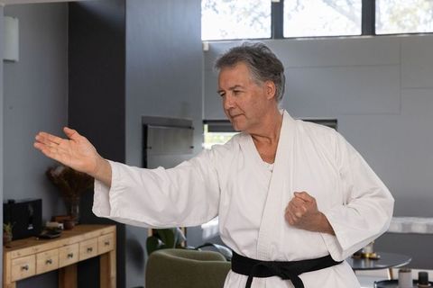 Senior man practicing karate at home for mindfulness and strength