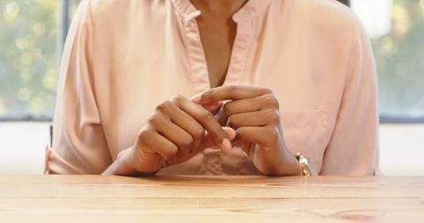 Elegant Woman Resting Hands on Table Wearing Light Pink Blouse