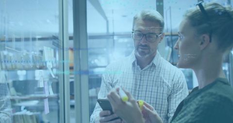 Co-workers brainstorming with digital technology in modern office