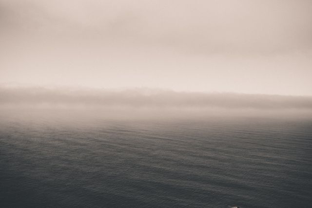 Capturing the view of a foggy horizon over a calm sea, creating a serene and tranquil atmosphere. The muted colors and minimalist design highlight the peacefulness of the scene. Ideal for use in projects related to nature, tranquility, solitude, and minimalism. Suitable for digital backgrounds, wallpaper, meditation themes, and artistic prints.
