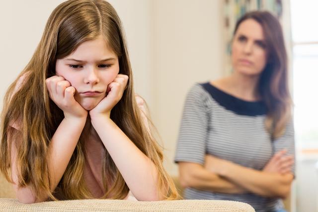 Daughter sitting upset with her mother in living room at home