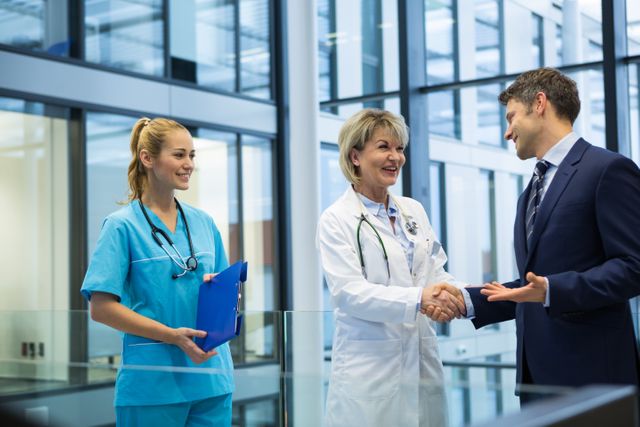 Female doctor shaking hands with businessman - Download Free Stock Photos Pikwizard.com