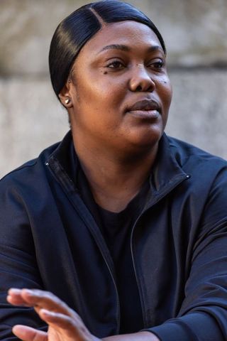 Thoughtful african woman headshot wearing black zip jacket urban minimalist portrait