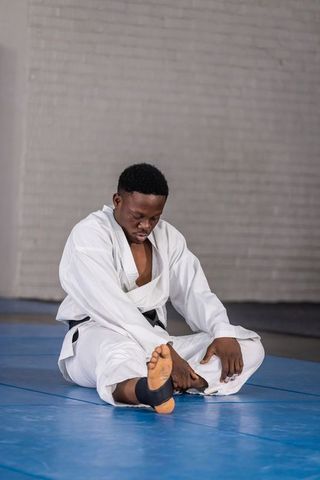 Man stretching in martial arts dojo wearing white gi