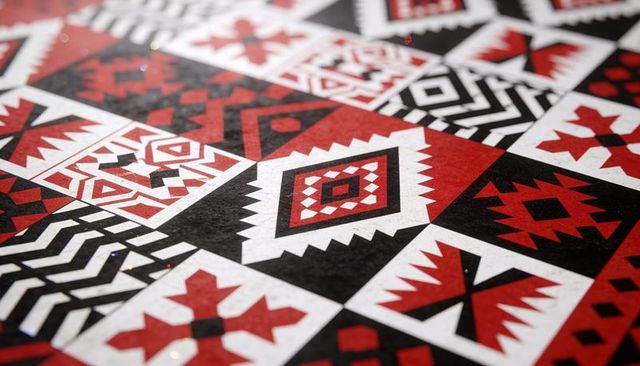 Geometric tile pattern featuring red black white diamonds, chevrons and tribal motifs