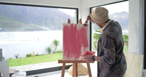 Indian Artist Painting Pink Abstract Strokes on Canvas in Bright Coastal Studio with Easel