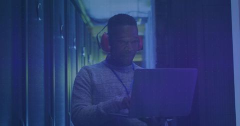 Technician in data center using laptop with digital data overlay