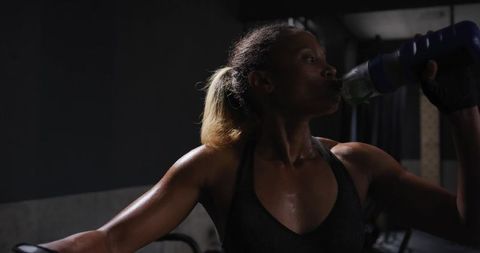 Female athlete hydrates during intense gym workout