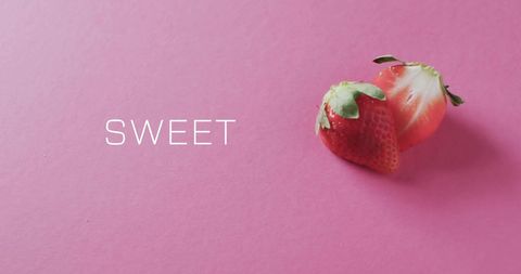 Halved strawberry on pink background with sweet text