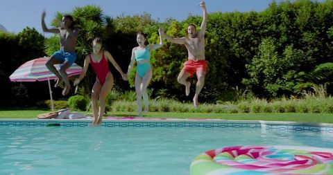 Friends Joyfully Jumping into Refreshing Backyard Pool