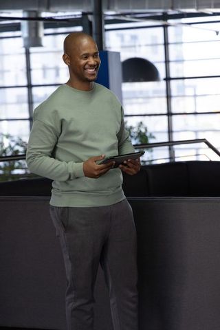 African american professional smiling and holding tablet in modern urban office lounge