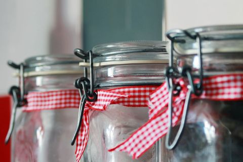 Row of three empty jars with gingham ribbon on shelf