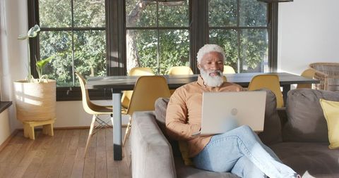 Senior man working on laptop in modern home interior