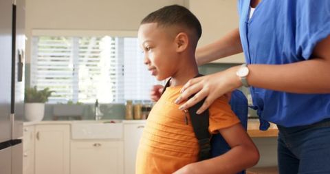 Mother Adjusting Son's Backpack in Bright Kitchen