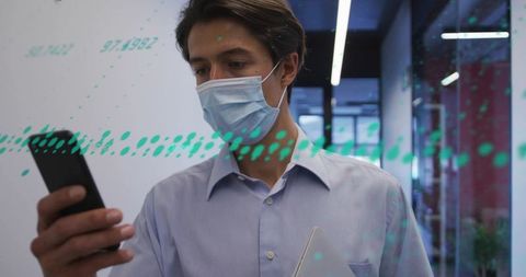 Young professional wearing mask checking smartphone holding tablet in modern office