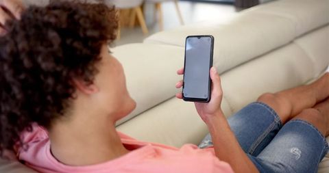 Young person relaxing on couch with smartphone