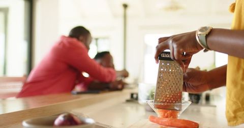 African american family cooking together, grating carrot on kitchen island in sunlit home