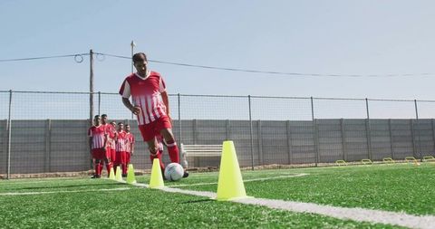 Soccer Player Dribbling Ball Through Cones in Training Session