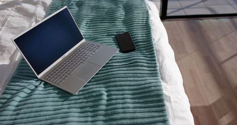 Minimalist Workspace with Laptop and Smartphone in Sunlit Bedroom