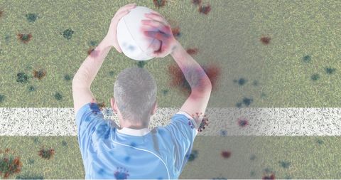 Rugby player holding ball amidst virus illustrations on field