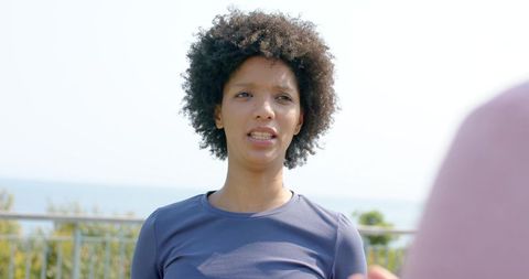 Diverse women talking on waterfront boardwalk during outdoor fitness walk