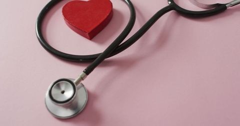 Stethoscope with red heart on pink background for love and health concept