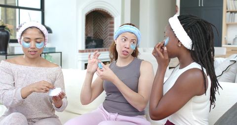 Diverse women enjoying under-eye hydrogel patch skincare party in cozy living room