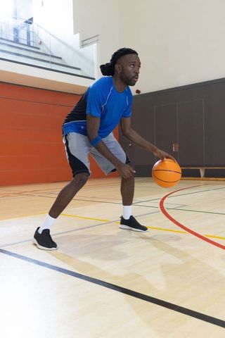 African american athlete dribbling basketball on indoor court showing focused intensity