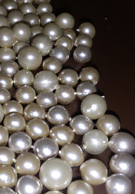 This image shows a detailed close-up of multiple white and ivory pearls with shiny surfaces. Ideal for themes related to fashion, jewelry, luxury, elegance, and beauty. Perfect for advertisements, brochures for jewelry shops, or as a background for luxury-brand promotional materials.