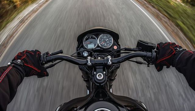 Riding motorcycle on winding rural road, first-person cockpit showing gauges and gps