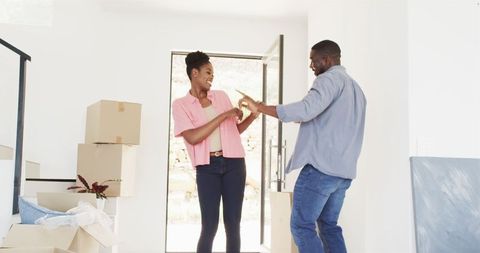 Joyful couple dancing in new home amidst moving boxes