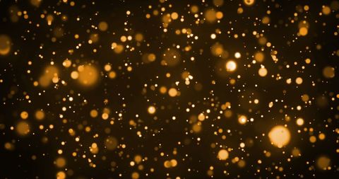 Golden bokeh particles against dark backdrop