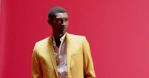 Stylish African American Man in Yellow Blazer Against Red Background