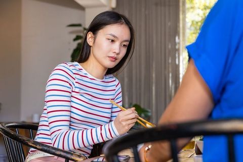 Young Woman Using Chopsticks for Dining in Cafe Setting