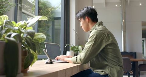 Professional Working on Laptop in Modern Greenery-Inspired Workspace