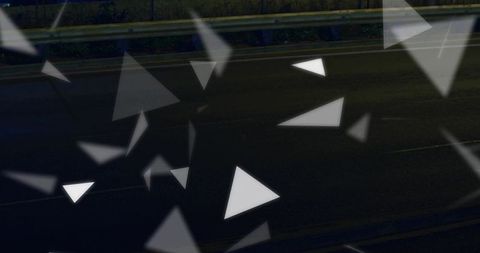 Floating geometric triangles drifting over dark highway asphalt with soft neon glow