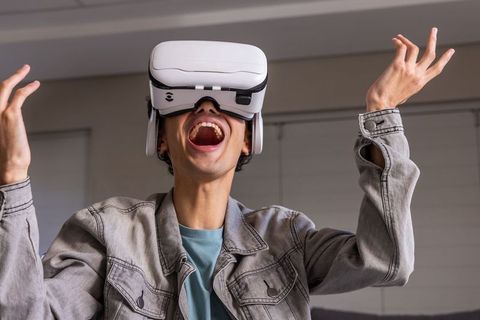 Teen male wearing white vr headset experiencing ecstatic virtual reality gaming reaction