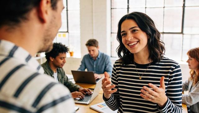 Smiling woman leading collaborative brainstorming session in open-plan modern office