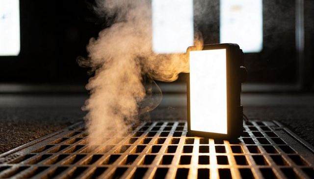 Backlit led panel casting warm steam over industrial metal grate, moody underground lighting