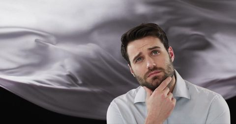 Caucasian man pondering in front of abstract floating fabric