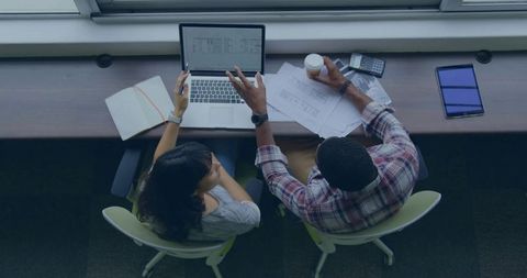 Collaborating on design plans reviewing laptop and printed blueprints with coffee