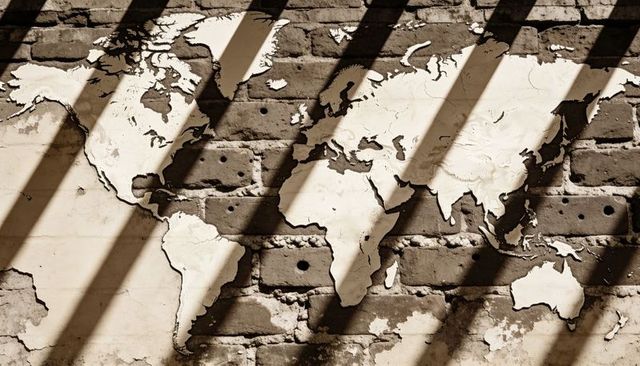 Vintage peeling world map mural on weathered brick wall with dramatic diagonal shadows