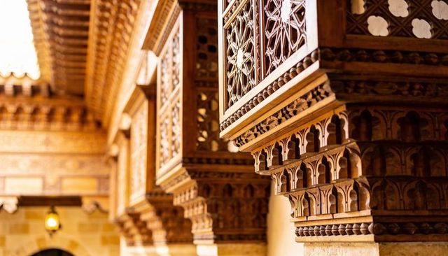 Ornate carved wooden balconies with lattice panels and lanterns in heritage interior